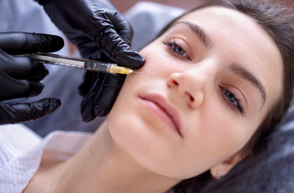 femme en train de faire une injection d'acide hyaluronique dans sa joue